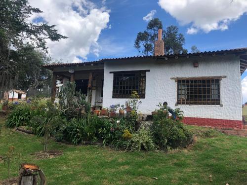 a white house with a garden in front of it at Finca El Pedregal Guatavita in Guatavita