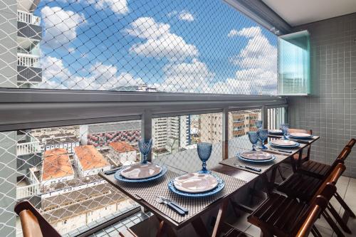 une salle à manger avec une table et des chaises et une grande fenêtre dans l'établissement Piemax Praia Grande - 100m PRAIA do BOQUEIRÃO e CENTRO - Vista MAR - Varanda GOURMET com CHURRASQUEIRA privativa - AR CONDICIONADO em todos os ambientes - Wi-Fi 600 Mbps - HOME OFFICE- Vaga de Garagem - Acomoda até 6 pessoas, à Praia Grande