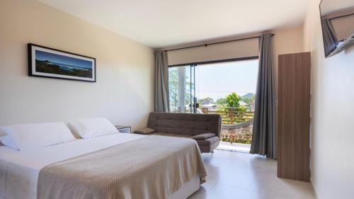 1 dormitorio con cama, sofá y ventana en Recanto Sol&Mar, en Praia do Rosa