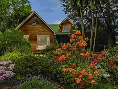 a wooden house with flowers in front of it at Kalimna Garden Room in Blackheath