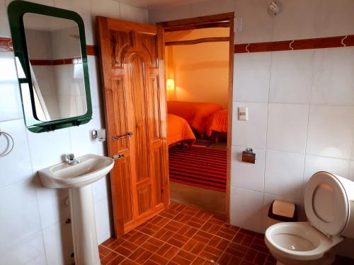 a bathroom with a toilet and a sink and a mirror at Wara Uta Lodge in Comunidad Yumani