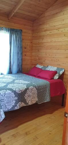 ein Schlafzimmer mit einem Bett in einer Holzhütte in der Unterkunft Cabaña Tio King in Uvita