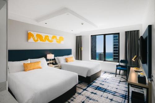 voco Gold Coast, an IHG Hotel في غولد كوست: غرفة فندقية بسريرين ومكتب