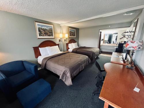 a hotel room with two beds and a desk and a couch at Ozark Inn & Suites in Ozark