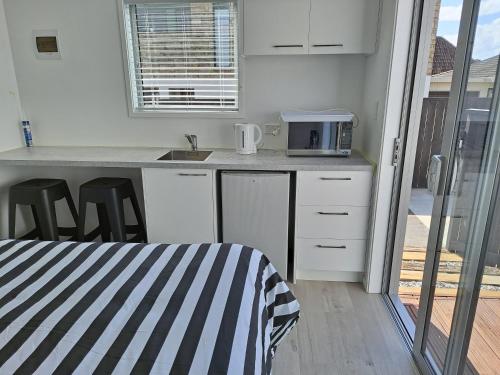 a kitchen with white cabinets and a counter top at Pod bach on Tweed in Tauranga