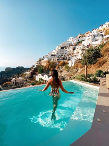 a woman in a swimming pool with a view of the ocean at Old Castle Oia in Oia