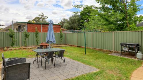 a patio with a table with an umbrella and a grill at Sun Centre Motel in Swan Hill