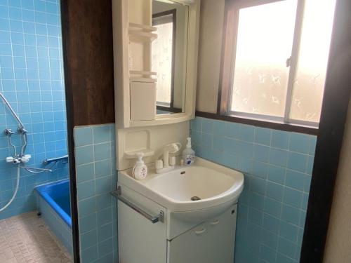 uma casa de banho azul com um lavatório e um espelho em 鉄道と山の見える家 em Yufu