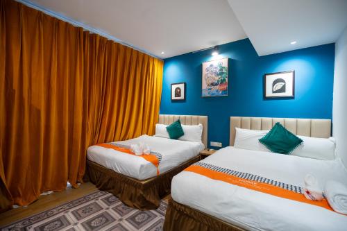 two beds in a room with blue walls and orange curtains at Apollo Inn in George Town