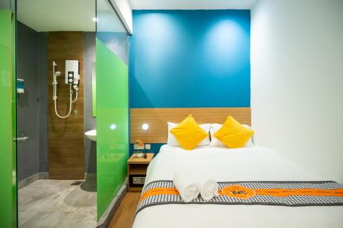 a bedroom with a bed with yellow pillows and a bathroom at Apollo Inn in George Town