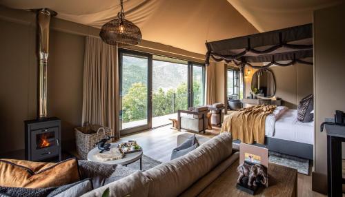 1 dormitorio con 1 cama y sala de estar con chimenea en Botlierskop Tented Lodge, en Reebok