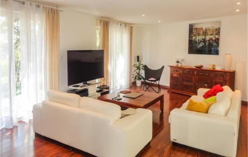 Il comprend un salon doté de 2 chaises blanches et d'une télévision à écran plat. dans l'établissement Lovely Home In Sussargues, à Sussargues