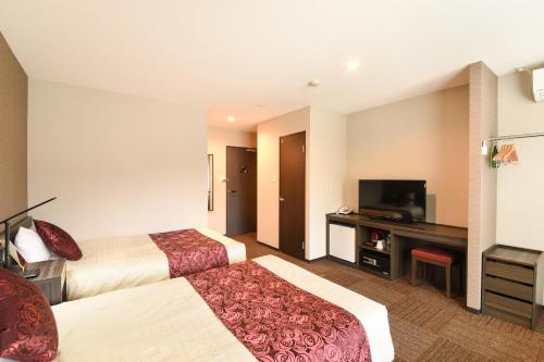 a hotel room with two beds and a flat screen tv at Arima Onsen Koki in Kobe