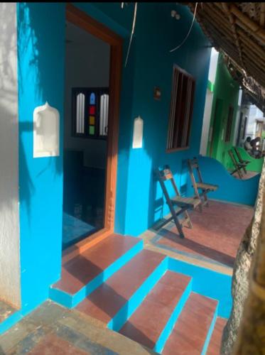 a room with a blue wall and a table and chairs at TANJORE HOME STAY in Thanjāvūr