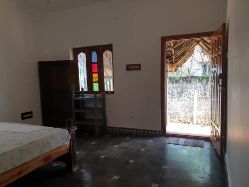 a room with a bed and a door with a window at TANJORE HOME STAY in Thanjāvūr