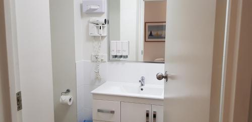 a white bathroom with a sink and a mirror at Reef Palms in Cairns