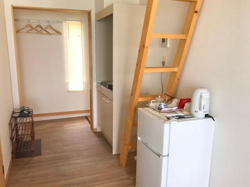 a small kitchen with a refrigerator and a ladder at Sea Breeze 1987 in Nagato