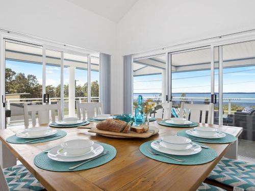 a dining room with a wooden table with a view of the ocean at Bay Views in Callala Bay
