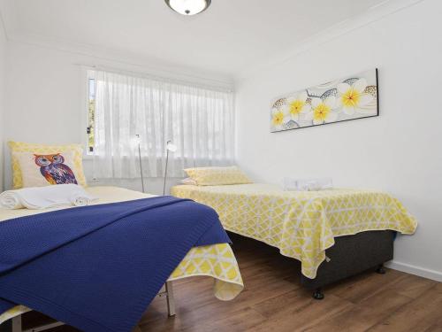 a bedroom with two beds with yellow and blue sheets at Bay Views in Callala Bay