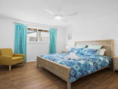 een slaapkamer met een bed en een gele stoel bij Bay Views in Callala Bay