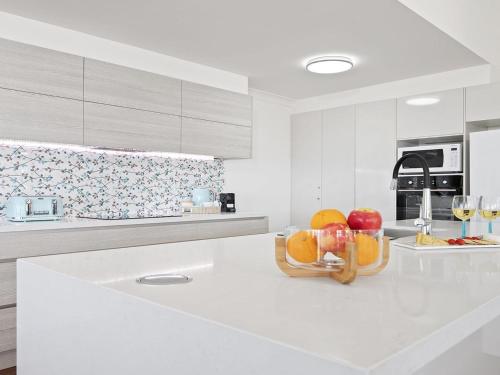 a white kitchen with a bowl of fruit on a counter at Bay Views in Callala Bay