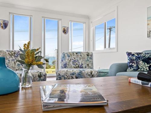 a living room with a table with a magazine on it at Bay Views in Callala Bay