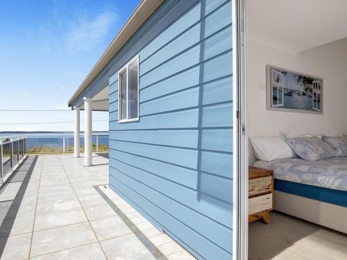 a blue garage door with a bed and a balcony at Bay Views in Callala Bay