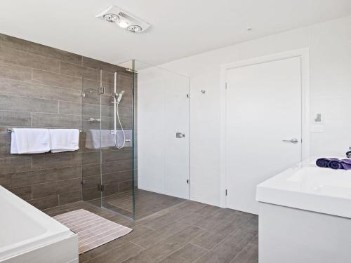 a white bathroom with a shower and a sink at Bay Views in Callala Bay