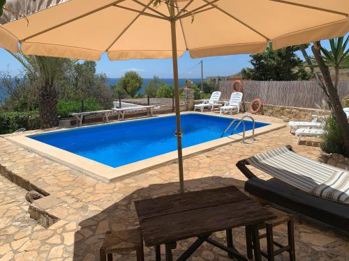 una piscina con ombrellone, due sedie a sdraio, tavolo e sidx sidx sidx di Villa Paiare a Torre Vado