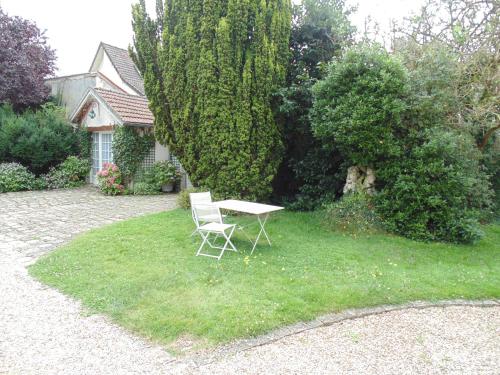 a table and a chair sitting in the grass at Clos Saint Nicolas in Neauphle-le-Château