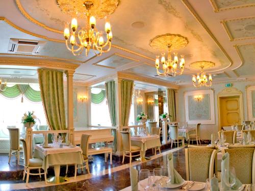 a restaurant with tables and chairs and chandeliers at Alleya Grand in Poltava