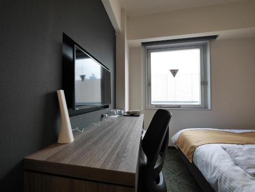 a bedroom with a desk and a bed and a window at Hotel Comfybed Ginza in Tokyo