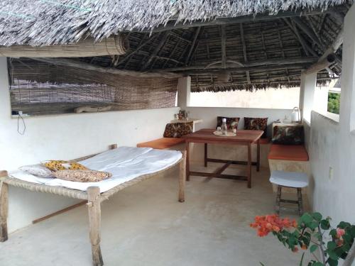 Shela的住宿－Furaha House，一间卧室设有一张床铺、一张桌子和稻草屋顶。