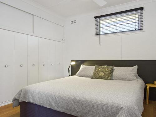 Un dormitorio con una cama con armarios blancos y una ventana. en Bellevue, en Culburra Beach