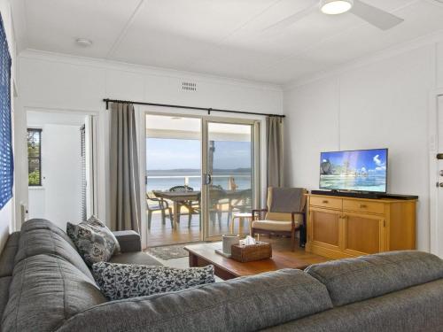 a living room with a couch and a television and a table at Bellevue in Culburra Beach