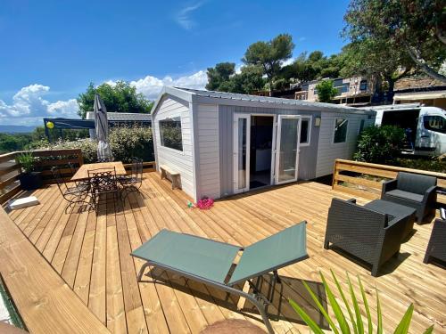 a deck with a tiny house with a table and chairs at Mobilhome 6 places vue mer in Drammont