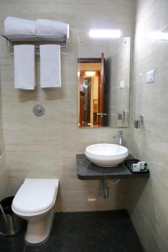 a bathroom with a sink and a toilet and a mirror at Hotel U.T.Elegance in Bangalore