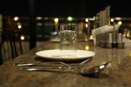 a glass of water on a plate with a spoon and fork at Hotel U.T.Elegance in Bangalore