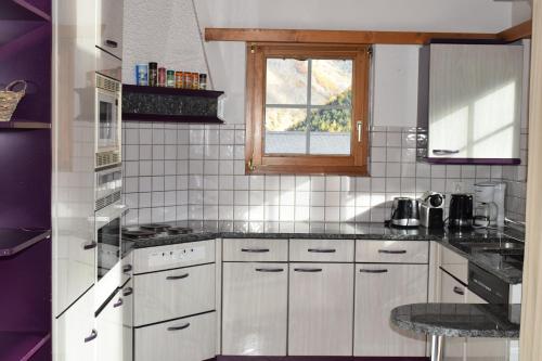 a kitchen with white cabinets and a window at Flamingo in Saas-Fee