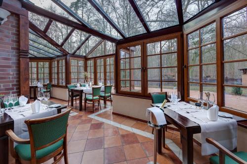 a dining room with tables and chairs and windows at Jagdschloss Waldsee in Waldsee