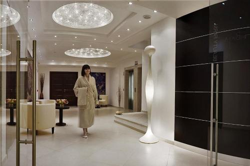 Una mujer está de pie en una habitación en un edificio en AHR Baja Hotel & Spa Cannigione en Cannigione