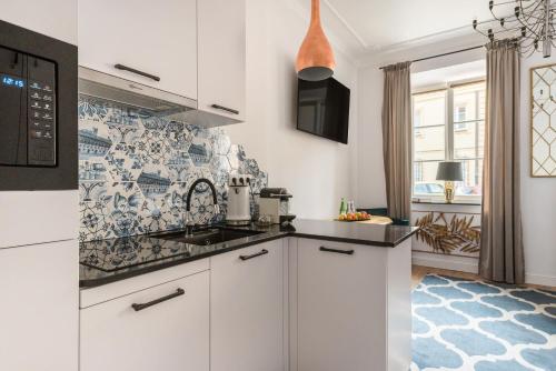 uma cozinha com armários brancos e uma parede de azulejos em ValdiArt Suites Old Town em Varsóvia