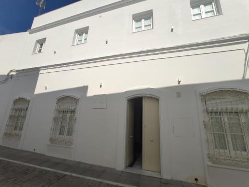 a white building with a door and windows at La Casa del Arco in Conil de la Frontera