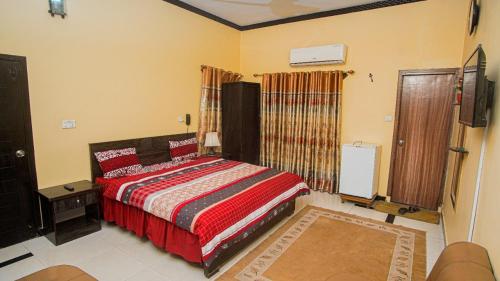 een slaapkamer met een bed met een rood dekbed bij Seasons Inn in Karachi