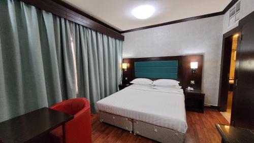 阿布達比的住宿－斯特朗德酒店，一间卧室配有一张床、一张桌子和一把椅子