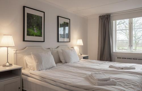 a bedroom with a white bed with two lamps and a window at Ekerum Resort Öland in Rälla