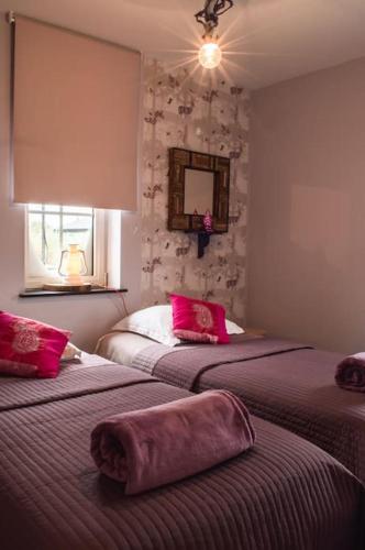 una camera da letto con due letti con cuscini rosa di De Pluktuin a Kortessem