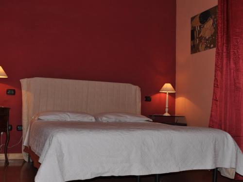 a bedroom with a white bed with red walls at Agriturismo La Prosciutta in Faenza