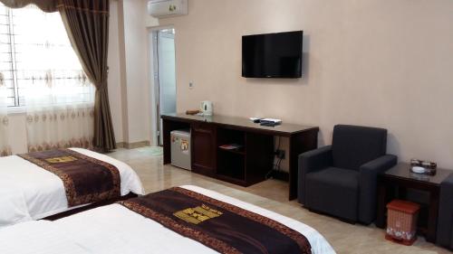 ドン・ヴァンにあるHOA CƯƠNG HOTEL - ĐỒNG VĂNのベッド、椅子、テレビが備わるホテルルームです。