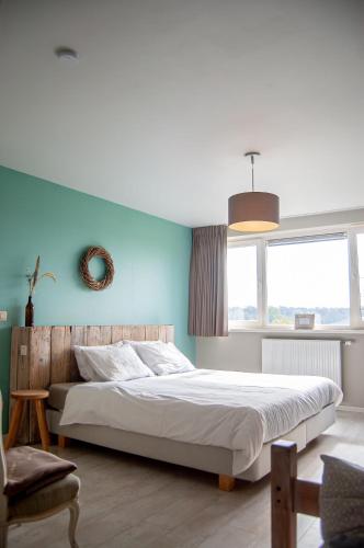 a bedroom with a large bed with a blue wall at LOGIES Tuin der Zinnen in Rijkevorsel